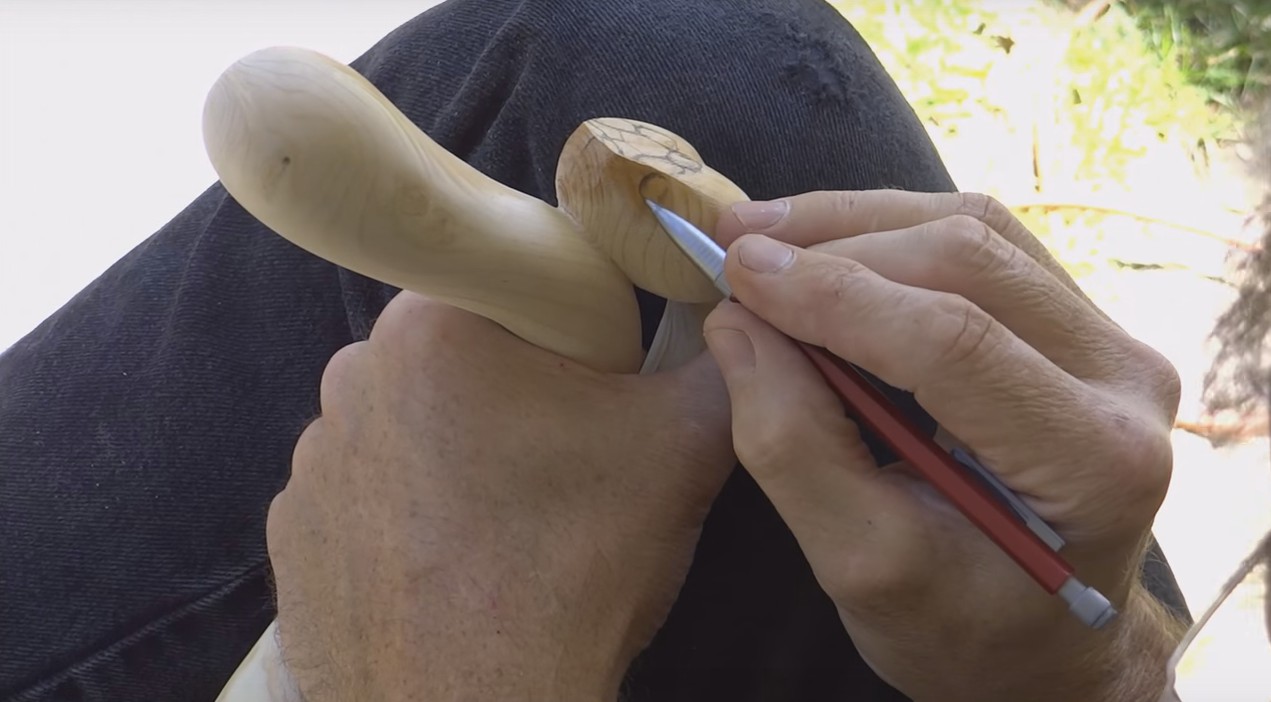 Столяр с прямыми руками вырезает деревянную трость со змеей